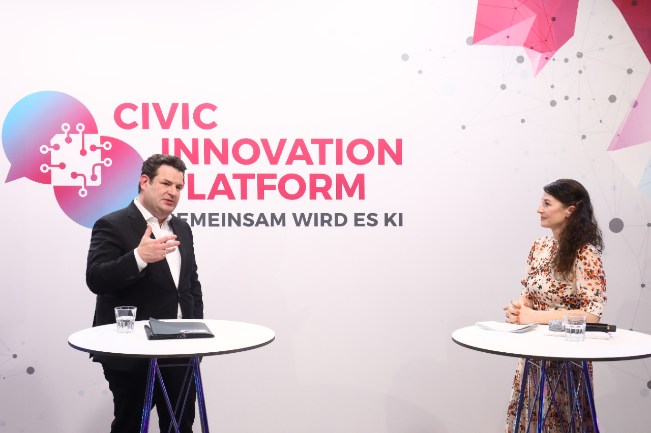Federal Minister of Labor Hubertus Heil stands in front of a wall with the logo of the Civic Innovation Platform and speaks.