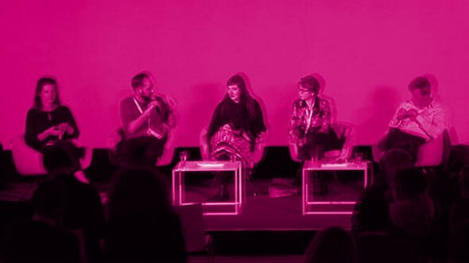 Diskussionspanel auf der Bühne, das Bild ist Pink eingefärbt