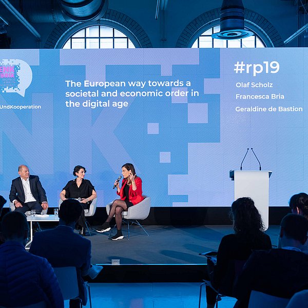 Olaf Scholz und drei Frauen sitzen auf der Bühne vor einer Rückwand mit dem Titel The European way towards a societal and economic order in the digital age.