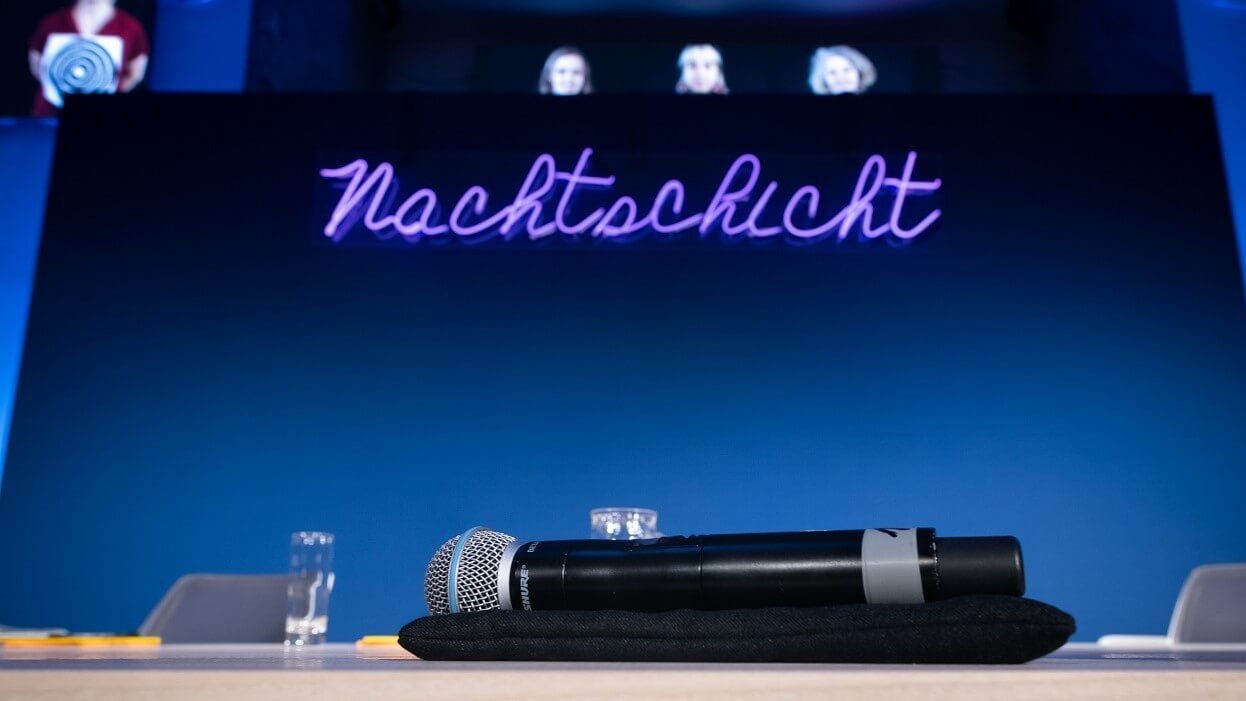 Ein Mikrofon auf dem Podium mit dem Nachtschicht-Schriftzug im Hintergrund